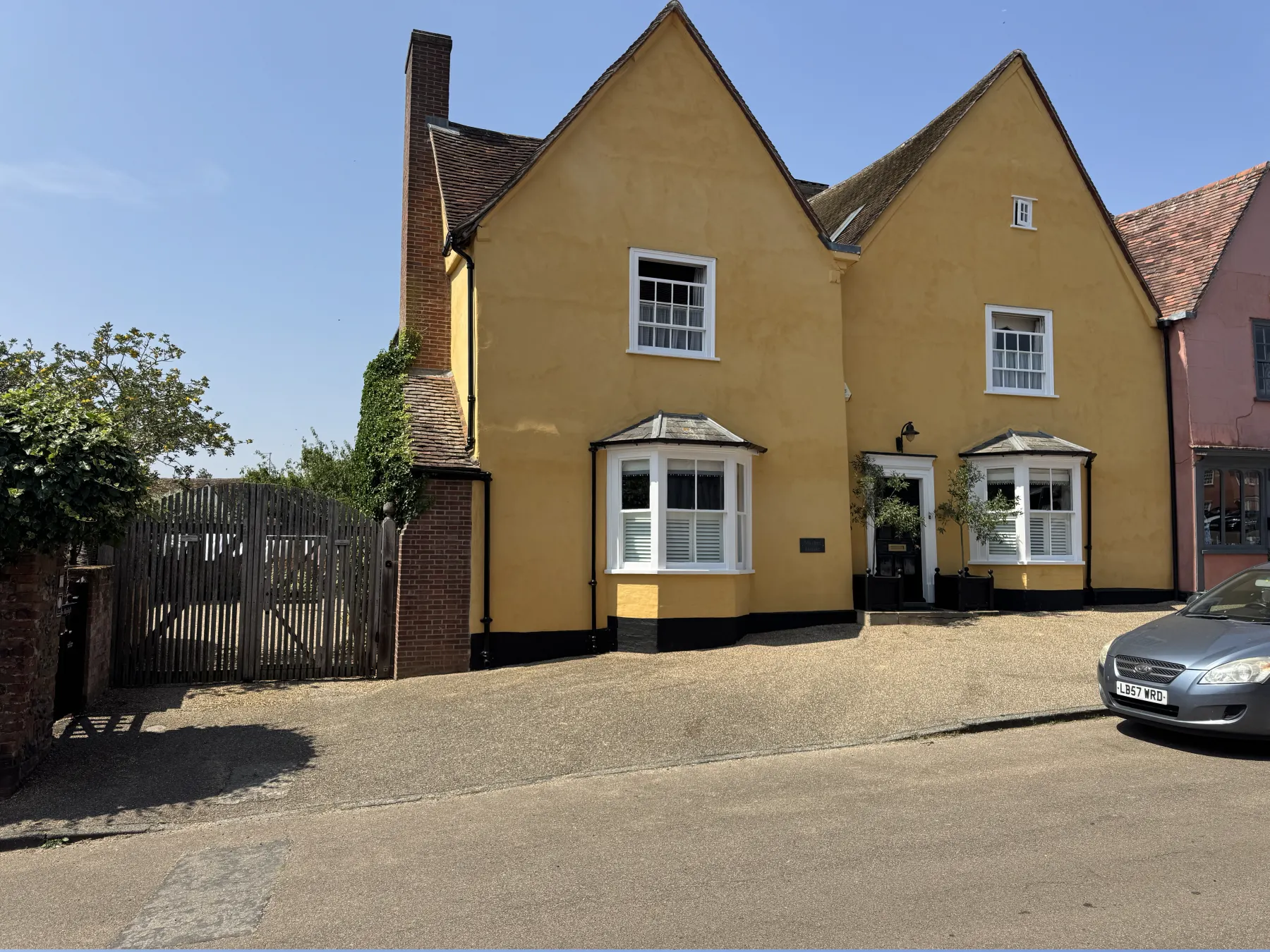 Left angled view of Lavenham period exterior showing chimney, gate and bay window
