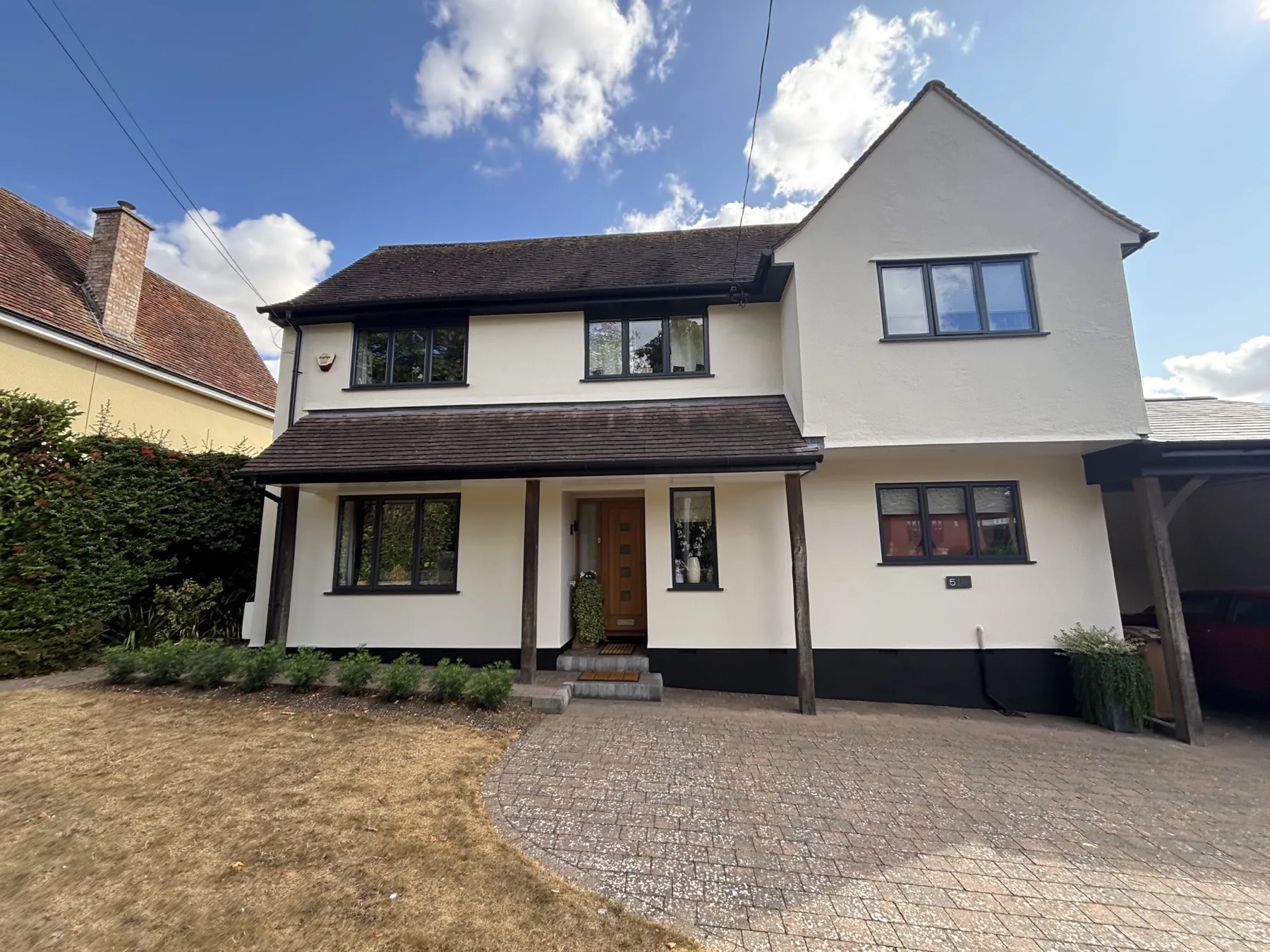 Completed exterior render on a detached house in Lavenham, cream finish with black trim and windows
