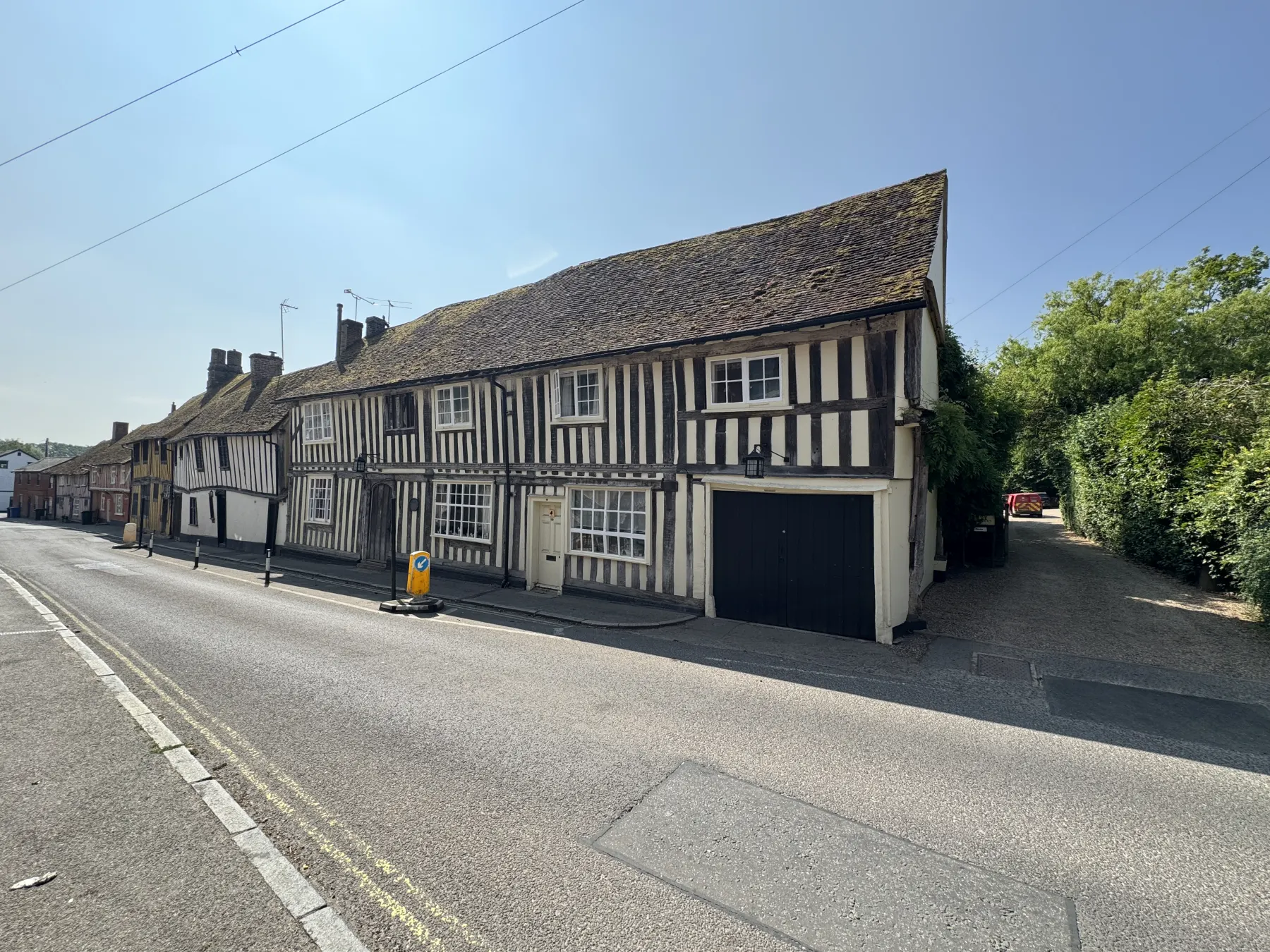 Wide street context showing timber-framed period property and neighbouring older buildings
