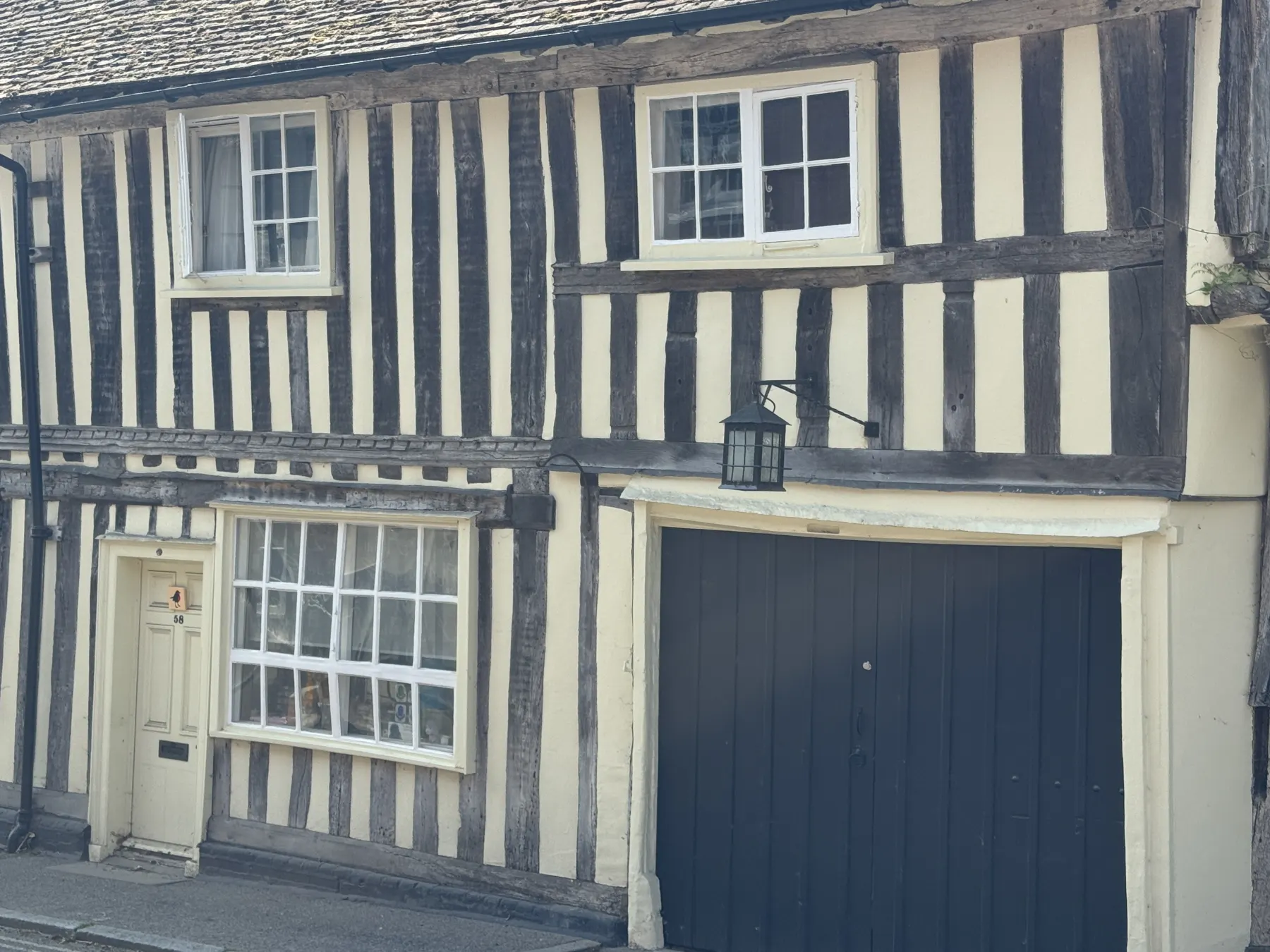 Timber-framed exterior detail with painted windows, cream panels and black door